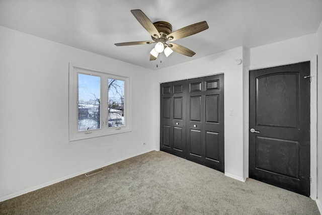 unfurnished bedroom with a closet, light colored carpet, and ceiling fan