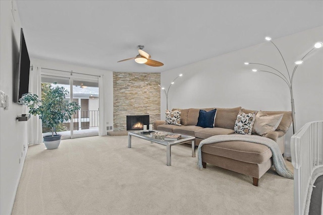 living room with light carpet, a stone fireplace, and ceiling fan