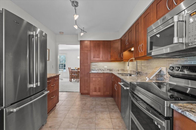 kitchen featuring light stone countertops, sink, backsplash, light tile patterned flooring, and appliances with stainless steel finishes