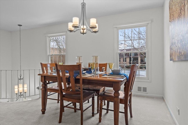 carpeted dining room with a chandelier