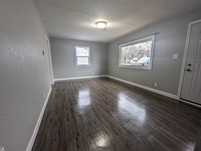 empty room featuring dark hardwood / wood-style flooring and a textured ceiling