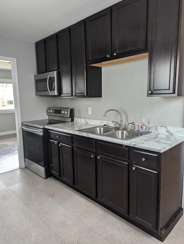 kitchen with stainless steel appliances, light stone counters, and sink