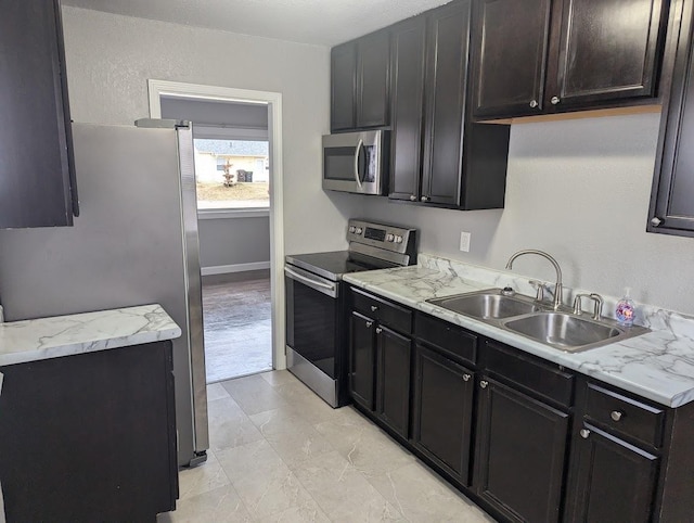 kitchen with light stone countertops, appliances with stainless steel finishes, and sink