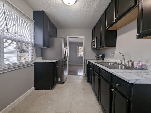 kitchen featuring appliances with stainless steel finishes, a textured ceiling, a wealth of natural light, and sink