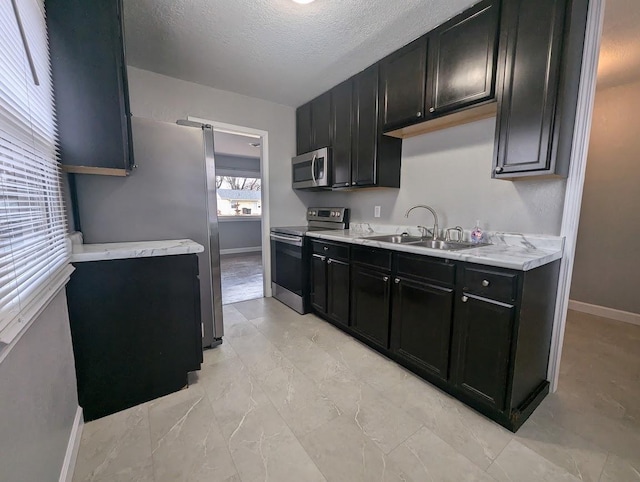 kitchen featuring a textured ceiling, sink, light stone countertops, and stainless steel appliances