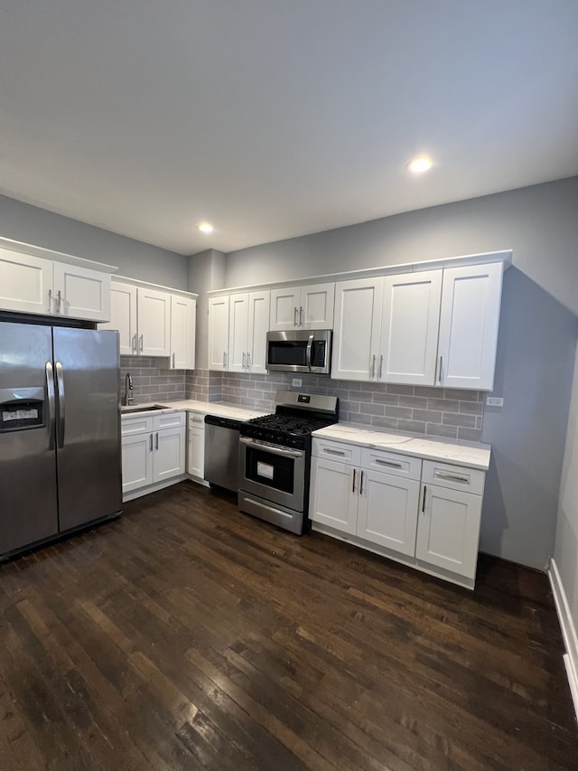 kitchen featuring appliances with stainless steel finishes, dark wood finished floors, light countertops, white cabinets, and recessed lighting