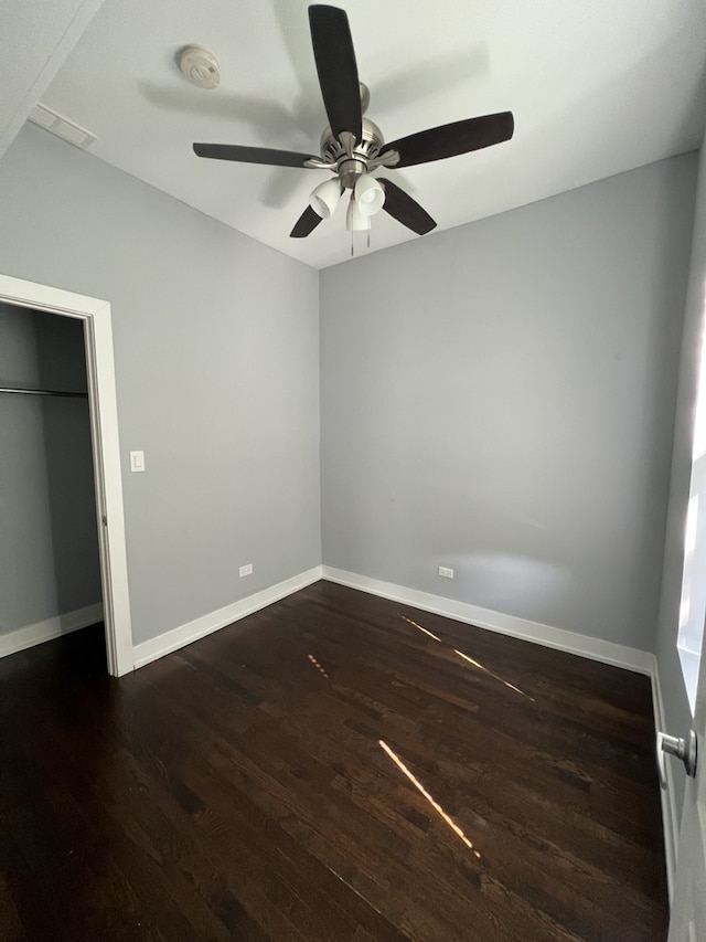 unfurnished bedroom with dark wood-type flooring, ceiling fan, and a closet