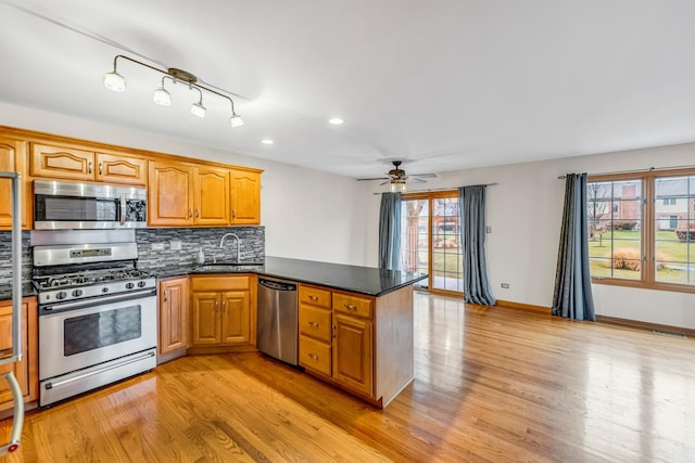 kitchen with sink, ceiling fan, appliances with stainless steel finishes, light hardwood / wood-style floors, and kitchen peninsula