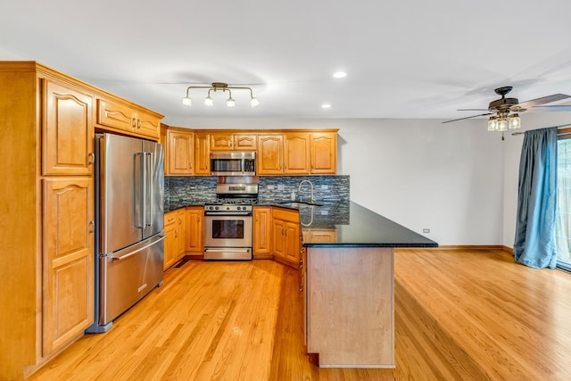 kitchen with kitchen peninsula, tasteful backsplash, stainless steel appliances, sink, and light hardwood / wood-style flooring