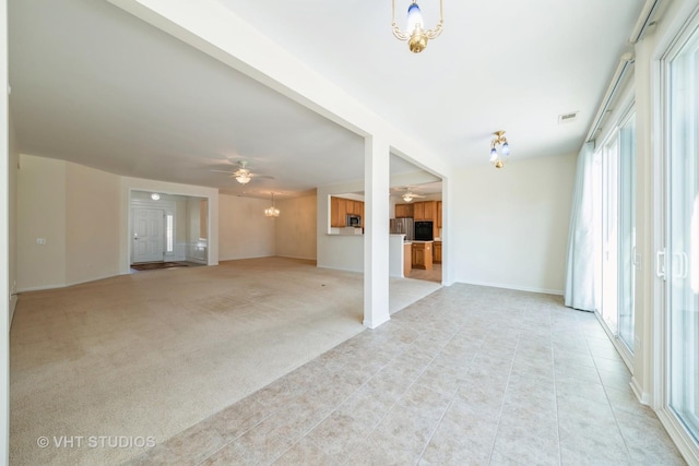 unfurnished living room with ceiling fan with notable chandelier and light colored carpet