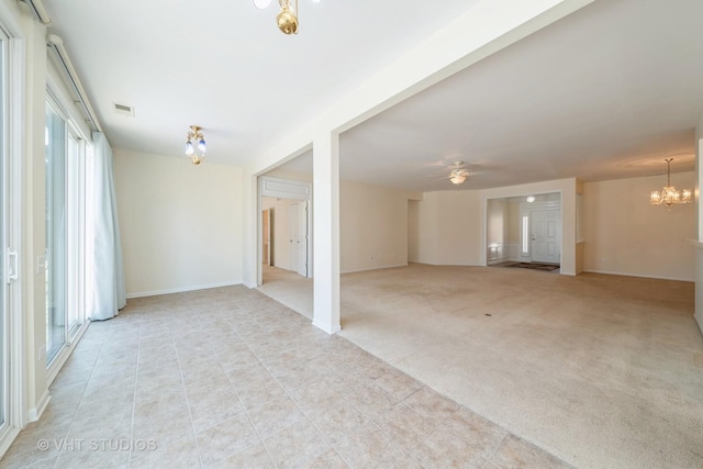 carpeted empty room with ceiling fan with notable chandelier