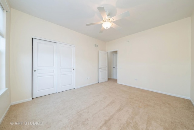 unfurnished bedroom featuring ceiling fan, light carpet, and a closet