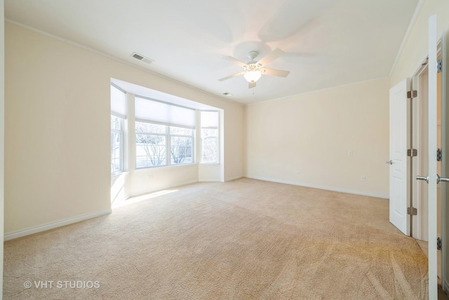 spare room featuring ceiling fan, light colored carpet, and crown molding