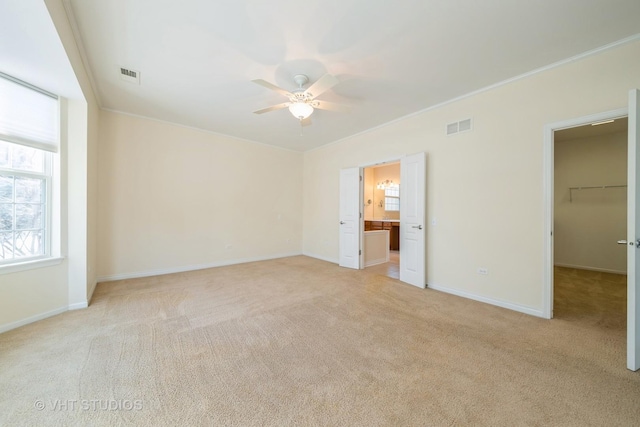 unfurnished bedroom featuring a walk in closet, ceiling fan, and crown molding