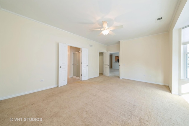 spare room featuring ceiling fan, light colored carpet, and crown molding