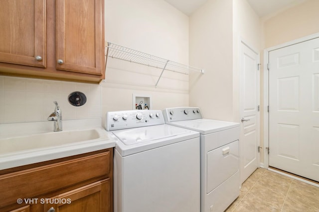 washroom featuring light tile patterned flooring, cabinets, sink, and washing machine and clothes dryer