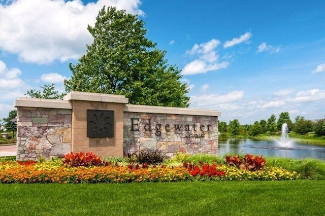 community / neighborhood sign featuring a yard and a water view