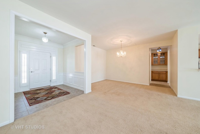 foyer entrance with light carpet, crown molding, and a notable chandelier