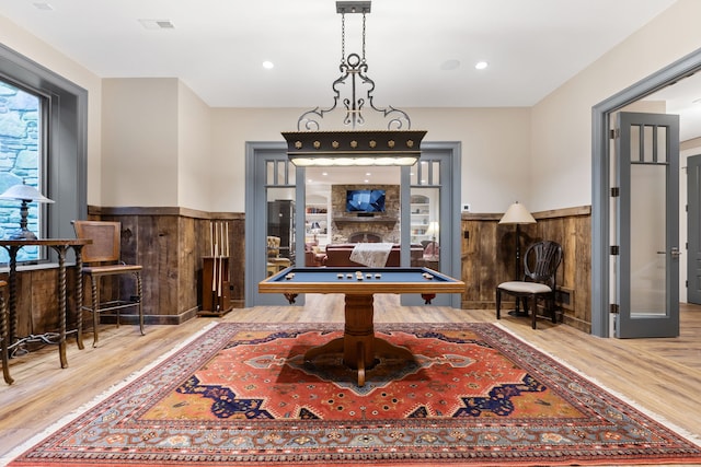 rec room with hardwood / wood-style flooring, billiards, and a stone fireplace