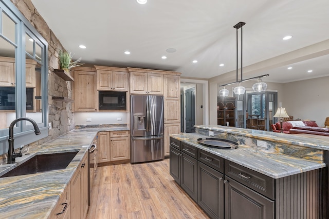 kitchen featuring stainless steel refrigerator with ice dispenser, light brown cabinets, black microwave, light stone countertops, and sink