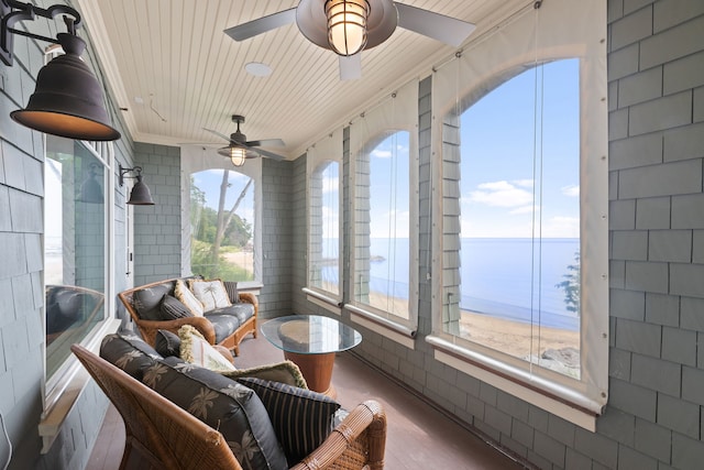 sunroom / solarium with ceiling fan, a wealth of natural light, wood ceiling, and a water view