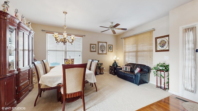 dining space with light hardwood / wood-style floors and ceiling fan with notable chandelier