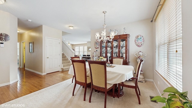 dining area with light wood-type flooring and an inviting chandelier