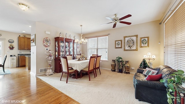 dining space featuring ceiling fan with notable chandelier and light wood-type flooring