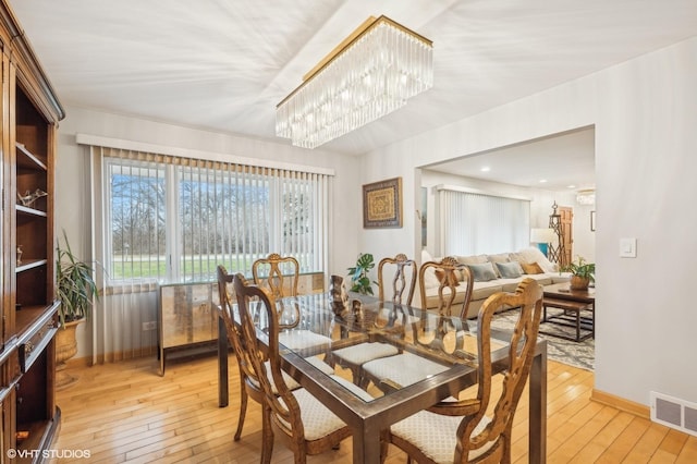 dining area with light hardwood / wood-style flooring and a notable chandelier