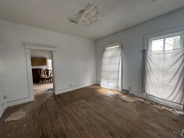 spare room featuring a healthy amount of sunlight and dark hardwood / wood-style flooring