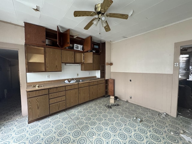 kitchen with dark brown cabinets, ceiling fan, ornamental molding, and sink