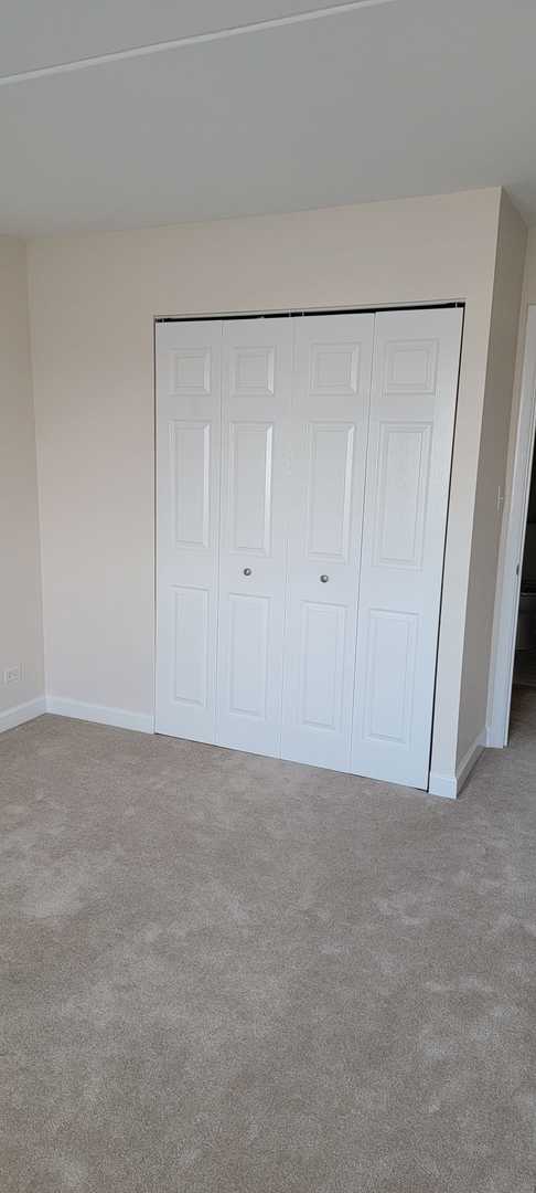 unfurnished bedroom with light colored carpet and a closet