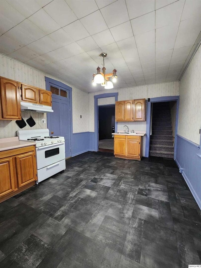 kitchen featuring an inviting chandelier, hanging light fixtures, sink, and white gas stove