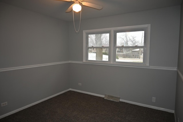 spare room with ceiling fan and dark carpet