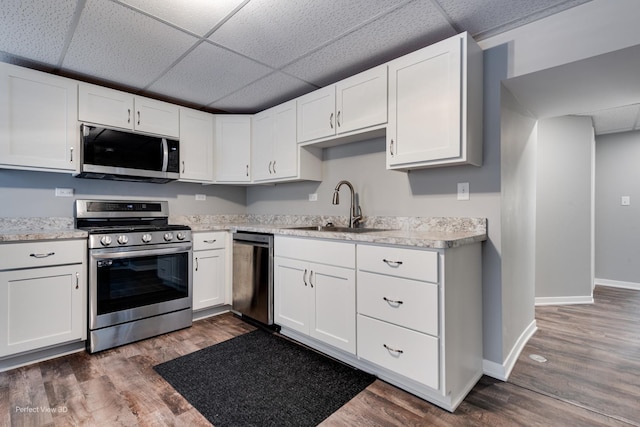 kitchen with appliances with stainless steel finishes, a paneled ceiling, sink, white cabinets, and dark hardwood / wood-style floors