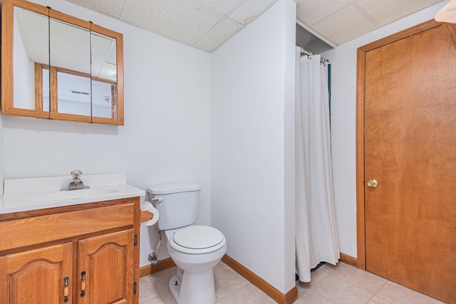 bathroom featuring tile patterned floors, a drop ceiling, toilet, and vanity