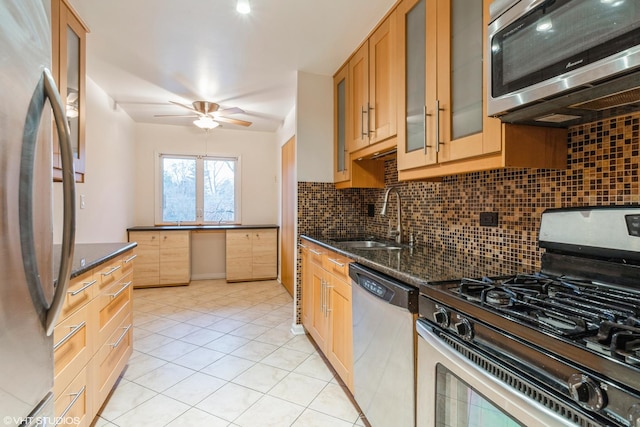 kitchen with backsplash, sink, ceiling fan, dark stone countertops, and stainless steel appliances