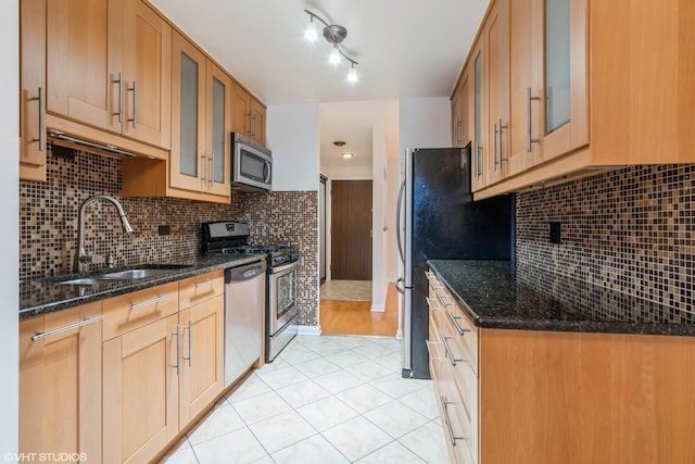 kitchen featuring light tile patterned floors, sink, appliances with stainless steel finishes, and dark stone counters