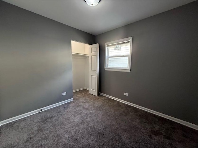 unfurnished bedroom featuring dark colored carpet and a closet