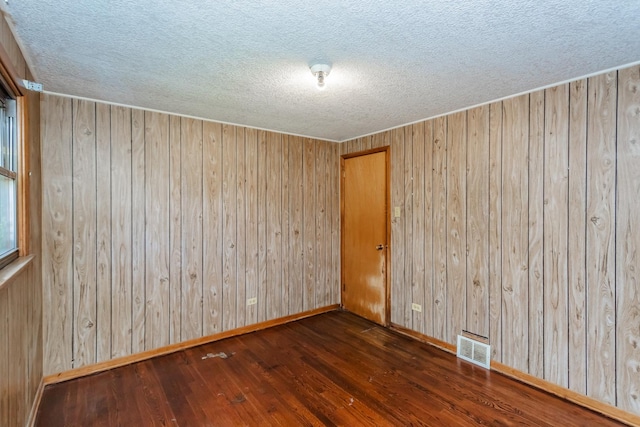 empty room with wood walls and dark wood-type flooring