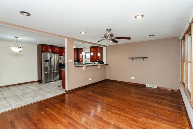 unfurnished living room featuring ceiling fan and light hardwood / wood-style floors