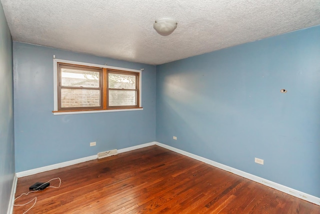 empty room with a textured ceiling and hardwood / wood-style flooring