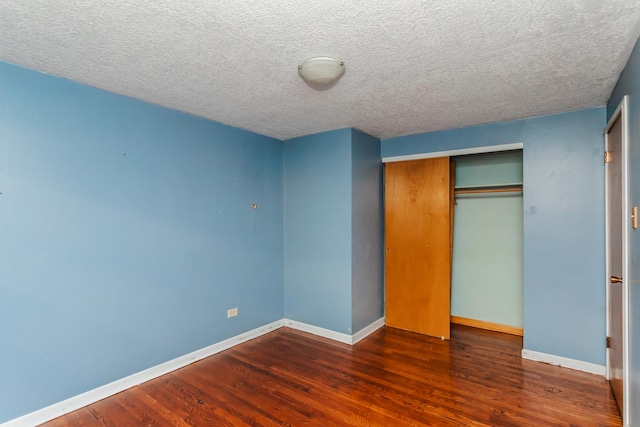 unfurnished bedroom featuring dark hardwood / wood-style flooring, a textured ceiling, and a closet