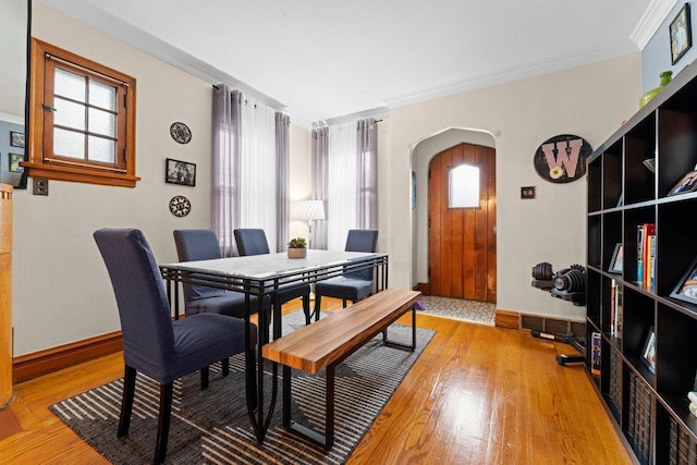 dining space featuring plenty of natural light, wood-type flooring, and ornamental molding