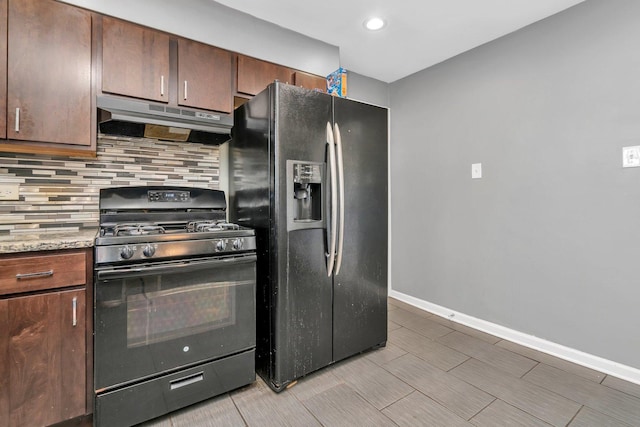 kitchen with backsplash, light stone countertops, and black appliances