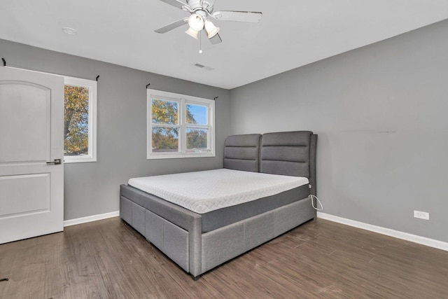 bedroom featuring multiple windows, dark hardwood / wood-style floors, and ceiling fan