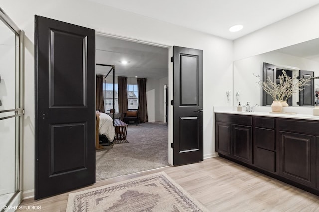 bathroom with hardwood / wood-style floors, vanity, and an enclosed shower