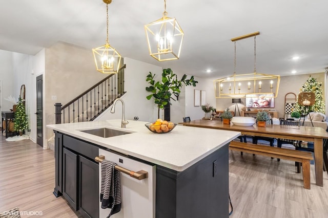 kitchen featuring a kitchen island with sink, sink, pendant lighting, and light hardwood / wood-style floors