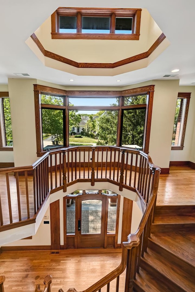 stairs featuring hardwood / wood-style flooring, plenty of natural light, and a raised ceiling