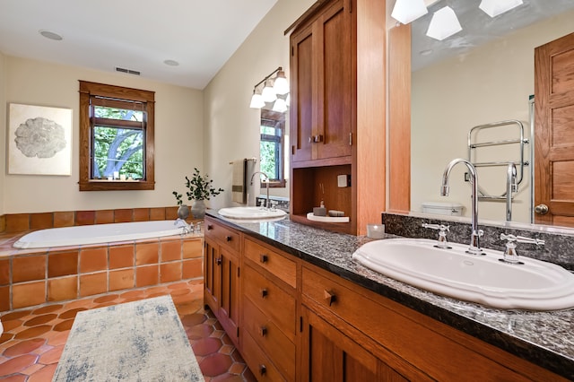 bathroom featuring tile patterned flooring, vanity, tiled bath, and toilet